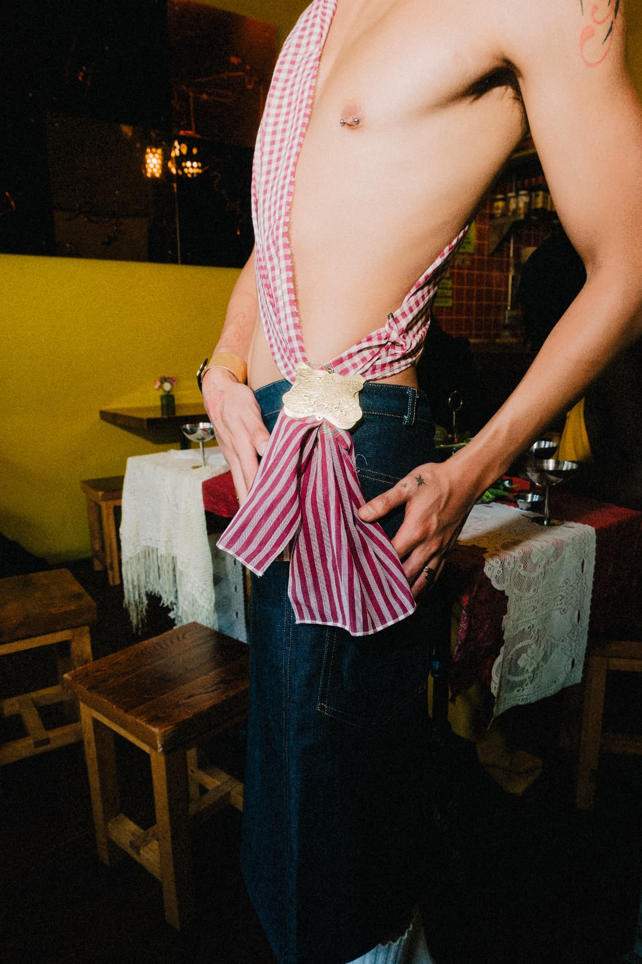 Pleated denim midi skirt with an engraved Apsara belt buckle and gingham drape.